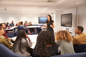 Female teacher addressing university students in a classroom